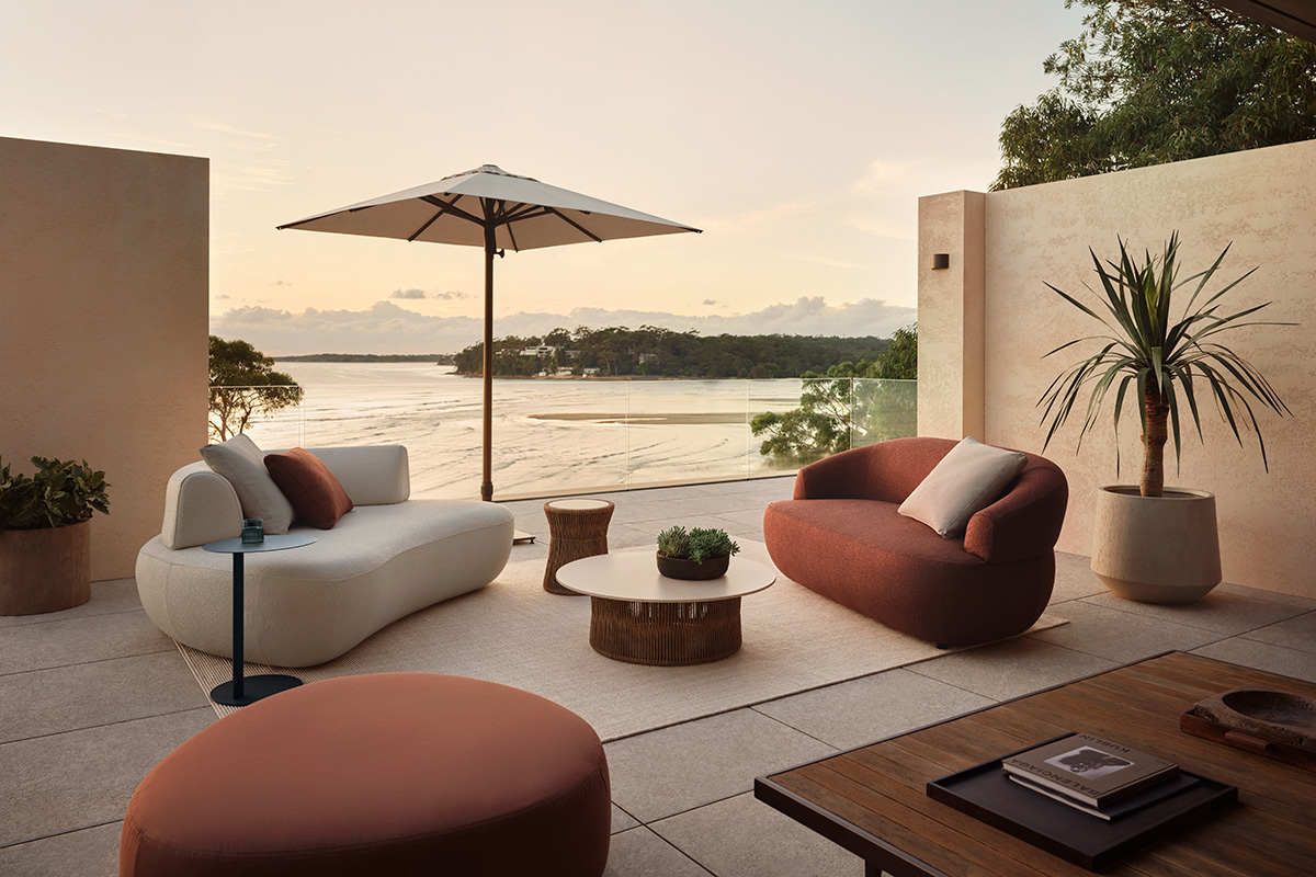 Aura Outdoor Sofas in Zenith Russet and Sable fabric, arranged around a low coffee table on a waterfront terrace.