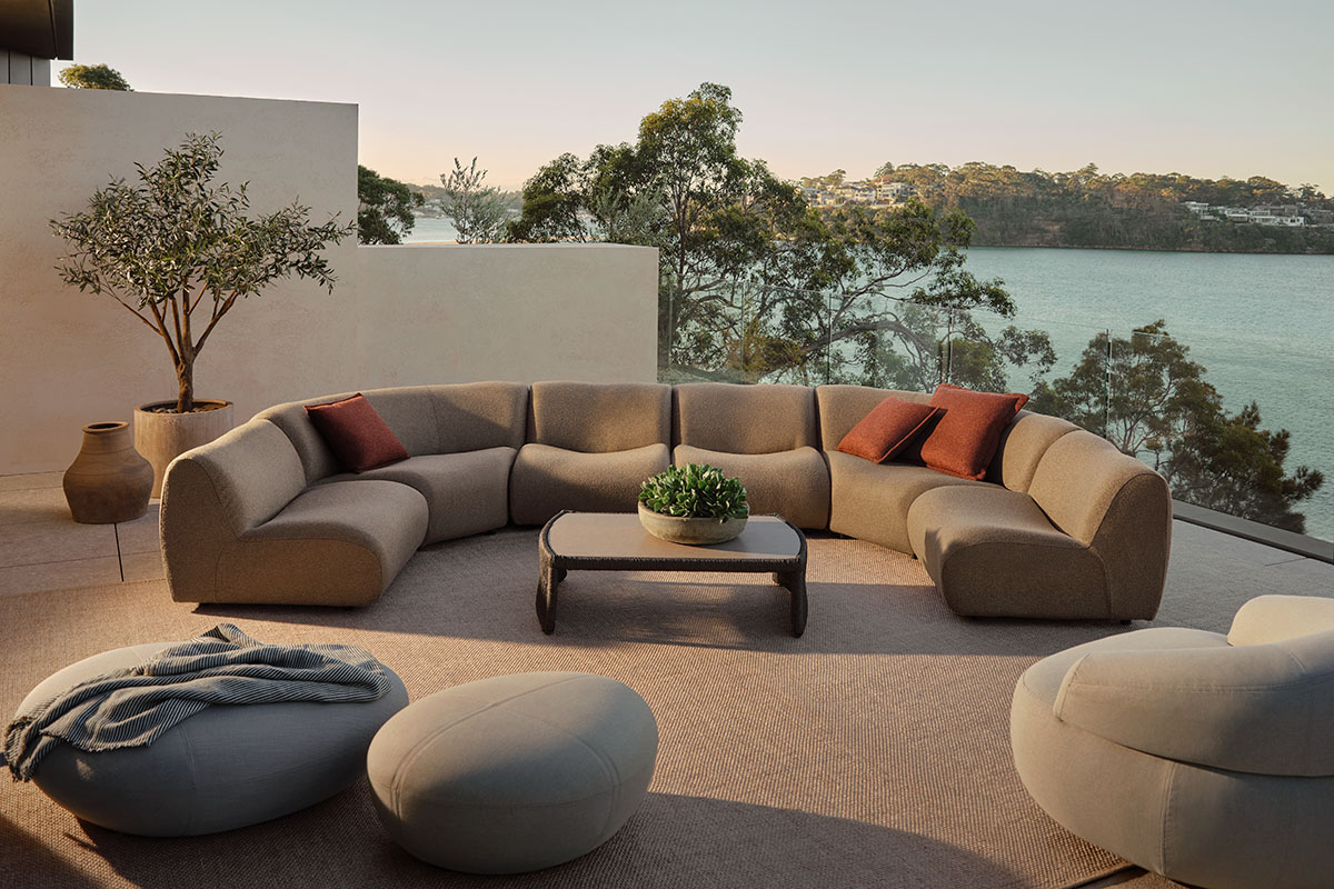 The 1977 Outdoor Sofa in a curved configuration on a coastal terrace. Styled in high-performance outdoor Zenith bouclé.