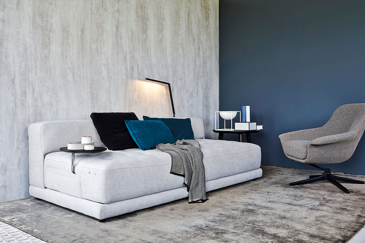 A small living space with a white sofa bed and grey occasional chair.