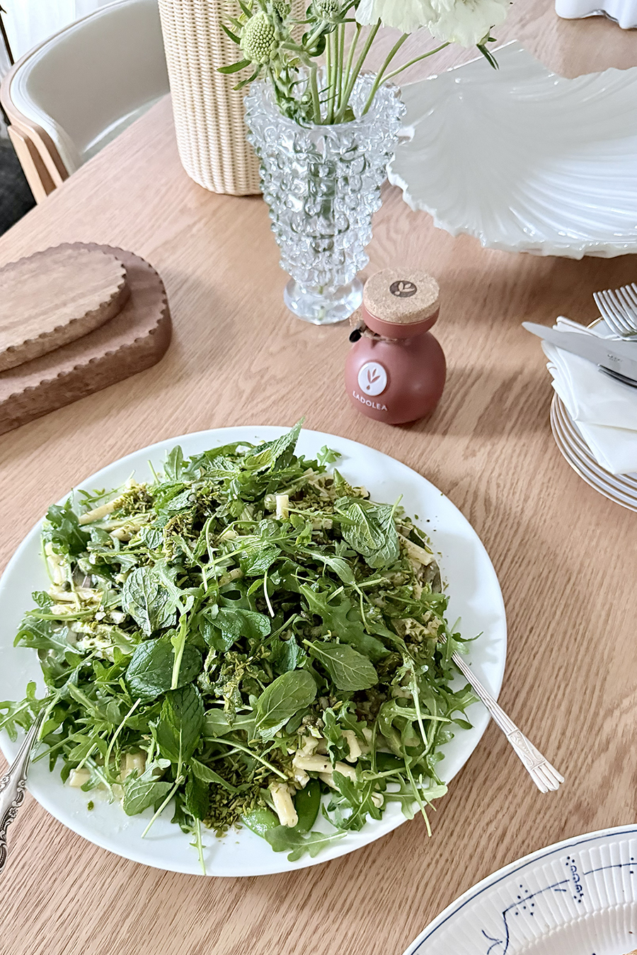 Fresh spring lunch or dinner of green pasta with rocket, mint and pistachio on a light timber table.